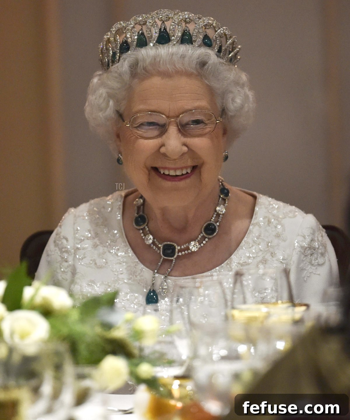 Queen Elizabeth II smiling, elegantly wearing the Vladimir Tiara with Cambridge Emeralds during a dinner in Malta, showcasing the enduring legacy of royal jewels.