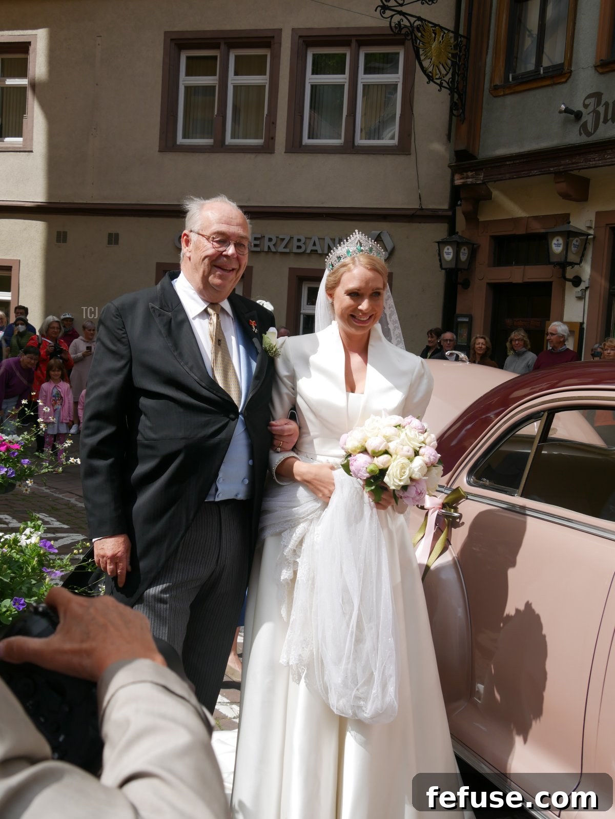 Germany's Princely Emerald Bridal Crown 3 Princess Amelie zu Löwenstein-Wertheim-Freudenberg gracefully arrives at her wedding ceremony on her father's arm, adorned in her beautiful bridal gown and family tiara.