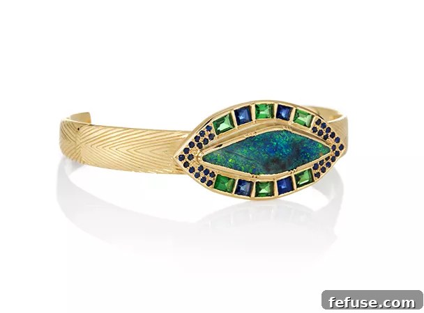 Brooke Gregson's Barragan Talisman cuff in 18k gold with a prominent boulder opal, emeralds, and sapphires