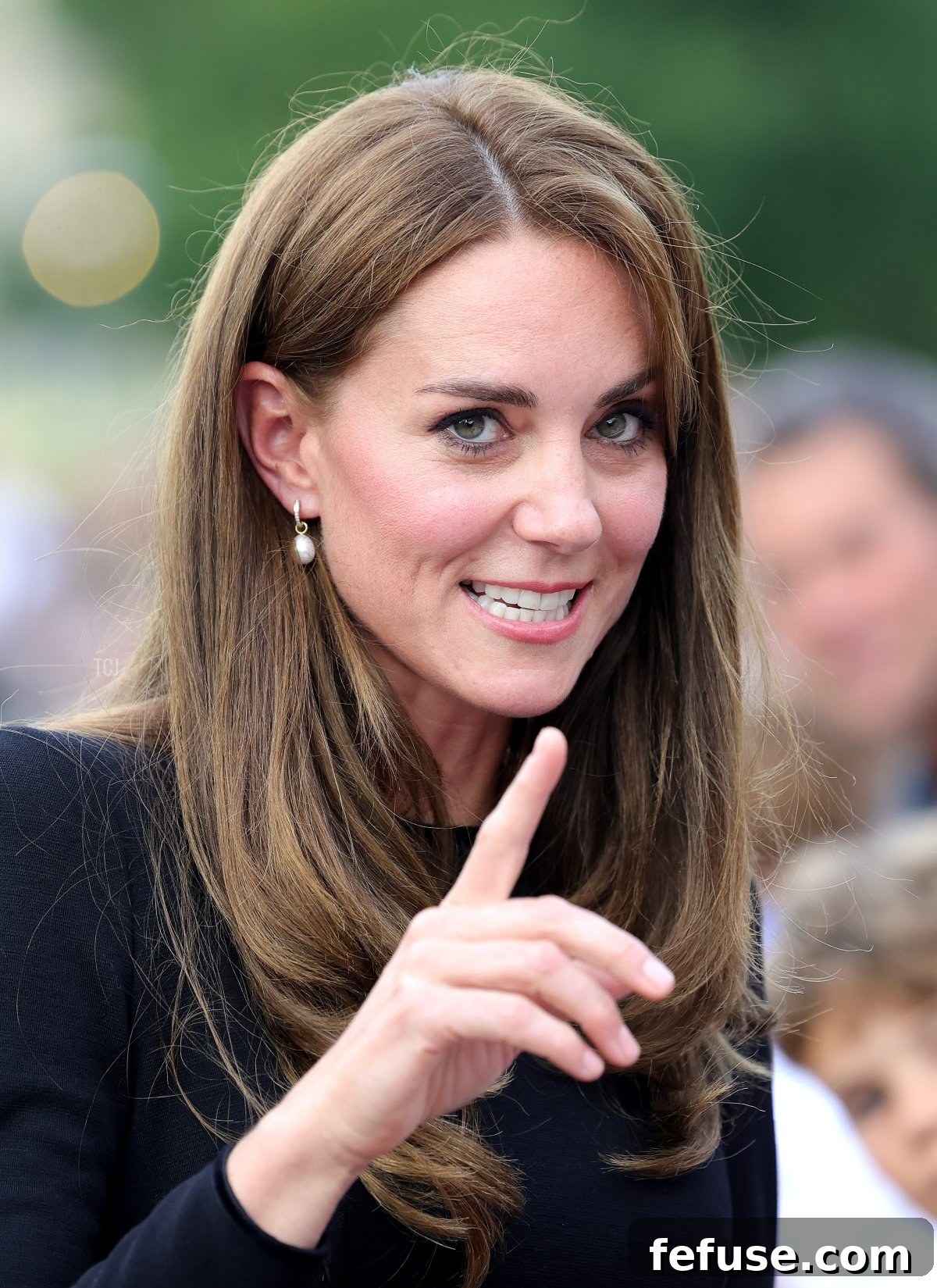Catherine, Princess of Wales, elegantly dressed in black, meets members of the public along the Long Walk at Windsor Castle, wearing subtle pearl and diamond earrings.