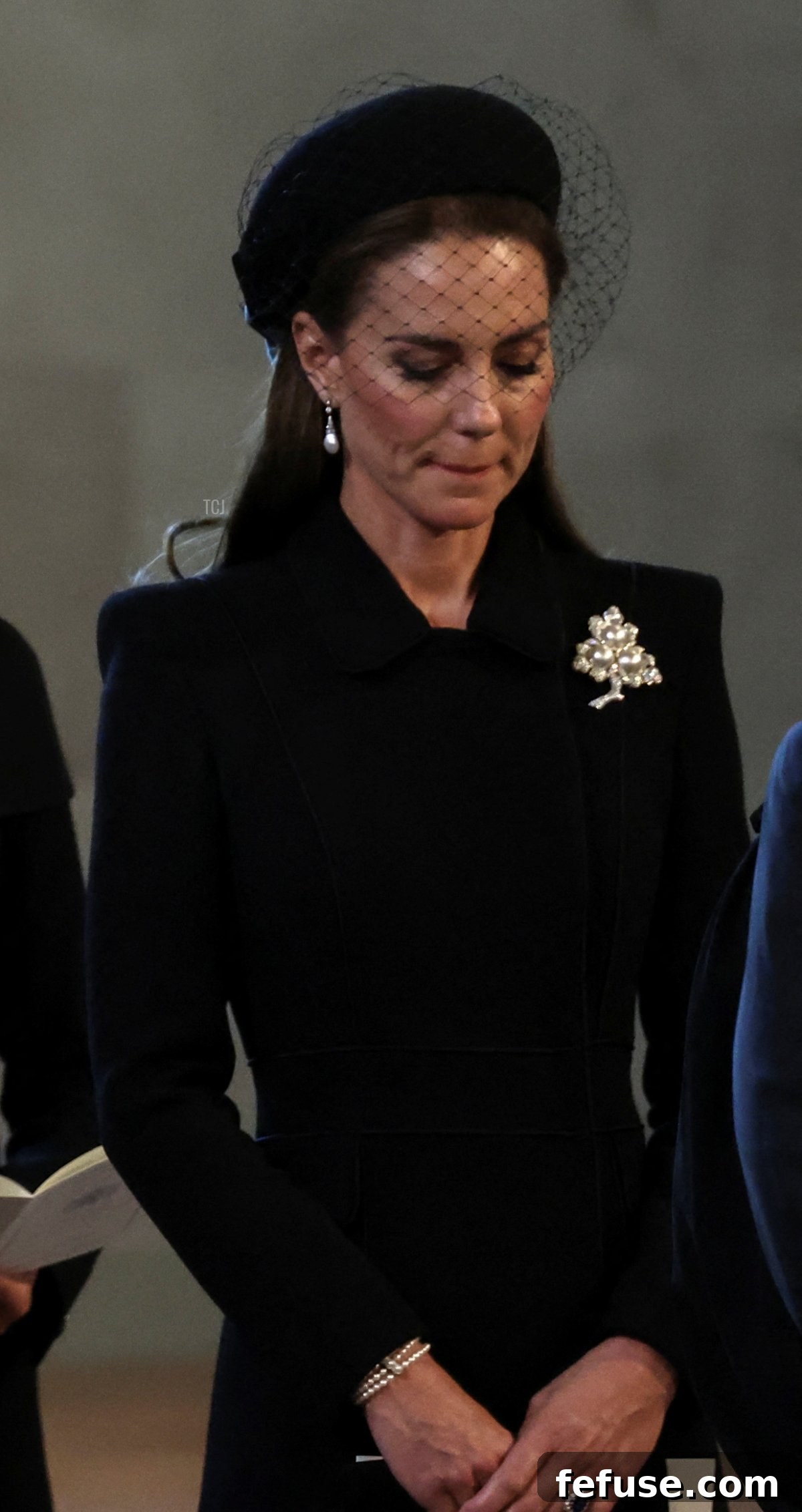 Catherine, Princess of Wales, stands with other royal family members during the ceremonial procession for Queen Elizabeth II, wearing a special pearl bracelet.