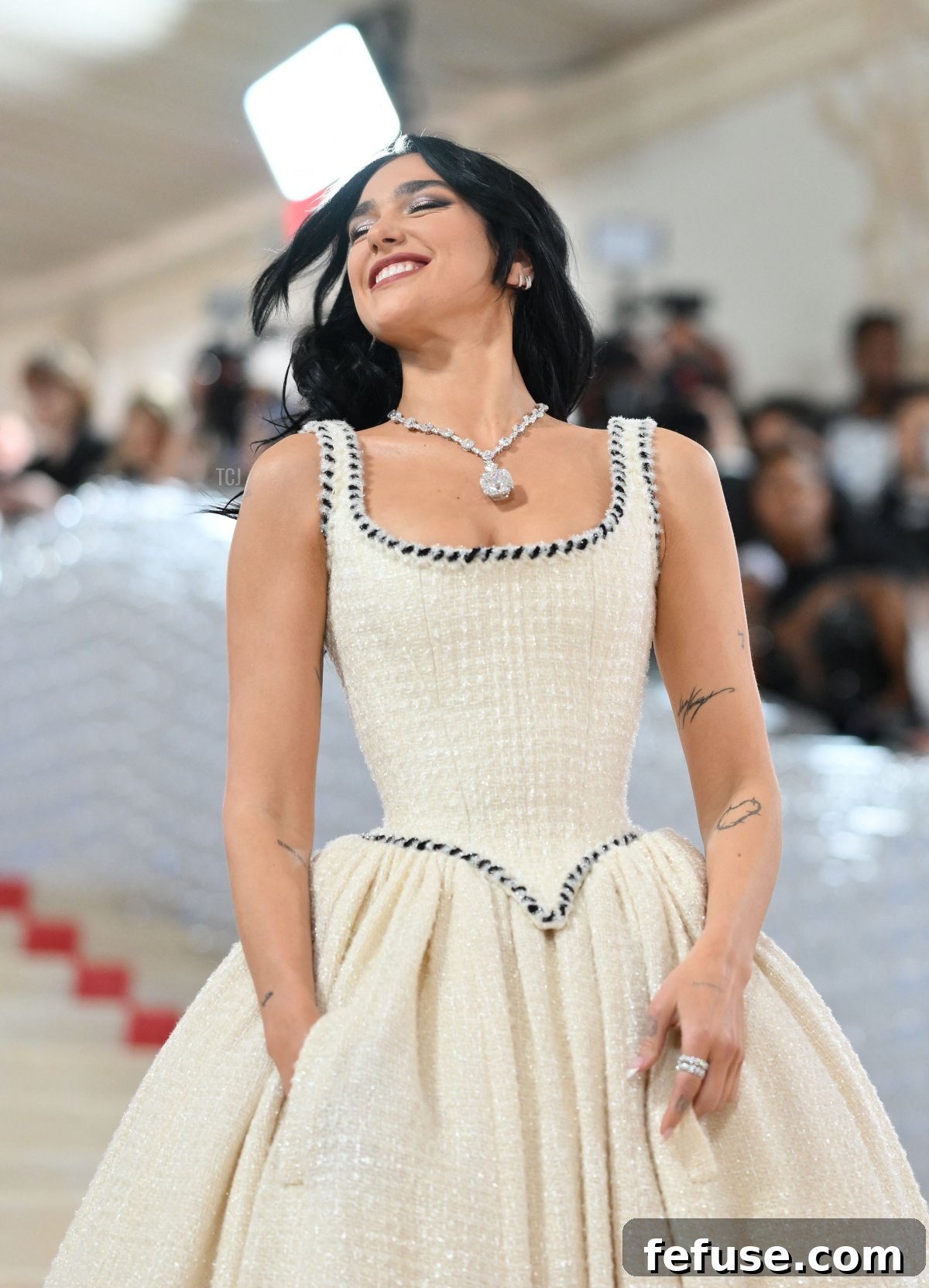 Dua Lipa exuding joy and confidence in her complete Met Gala 2023 look, featuring a beautiful Chanel gown and incredible Tiffany diamonds.