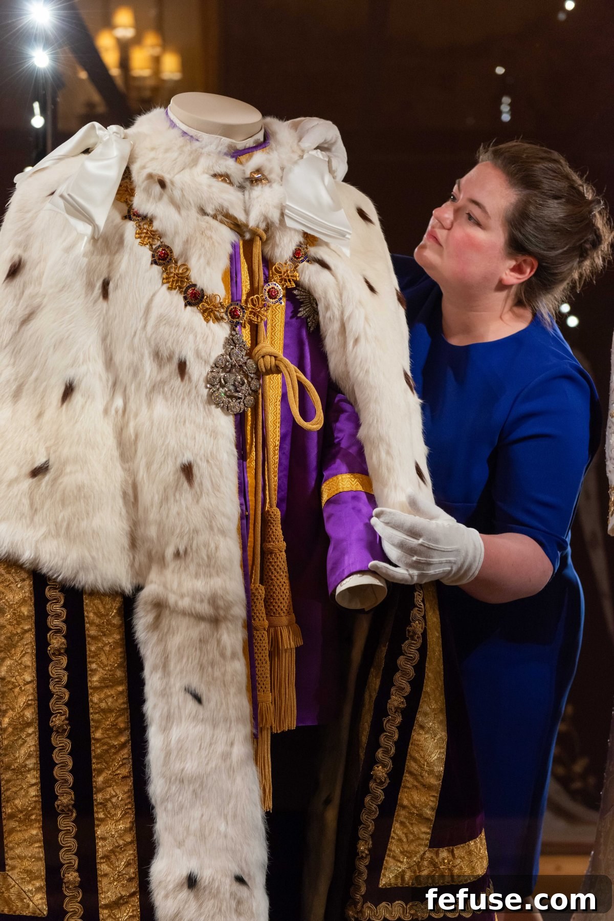 Detail view of King Charles III's coronation overshirt and Purple Coronation Tunic, highlighting the intricate embroidery and gold lace at the Buckingham Palace exhibition, July 2023. (Royal Collection Trust)