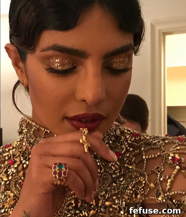 Priyanka Chopra's 2018 Met Gala makeup, featuring shimmering gold glitter on her eyes and arms, harmonizing with the deep burgundy of her outfit.